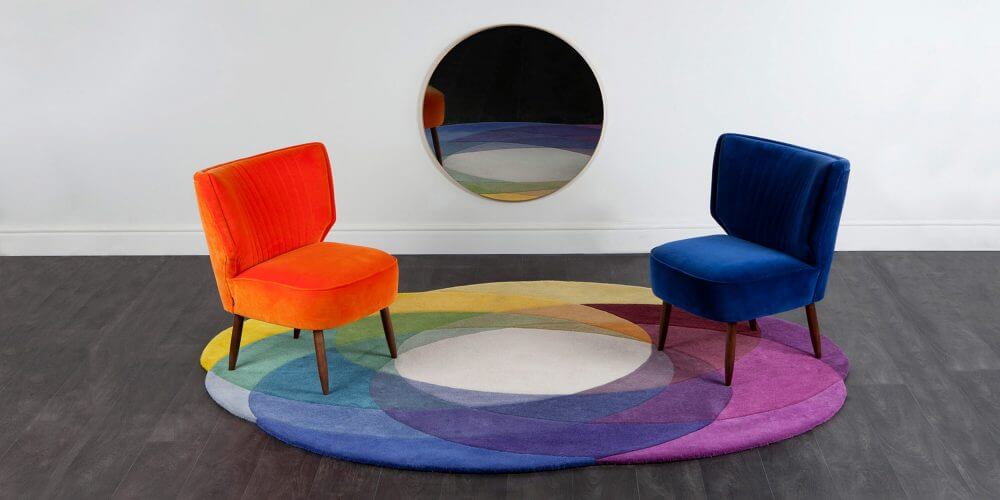 Sonya Winner vibrant contemporary Colour Wheel rug shown in a modern design setting with orange and blue armchairs