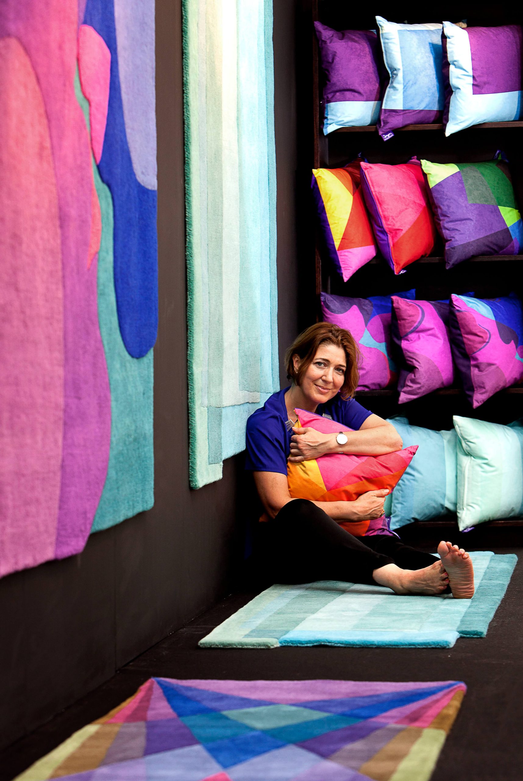 Portrait of contemporary British rug designer Sonya Winner with her vibrant wool rugs Kiss Tender, Rainbow and Aqua Teal Sea during London Design Fair