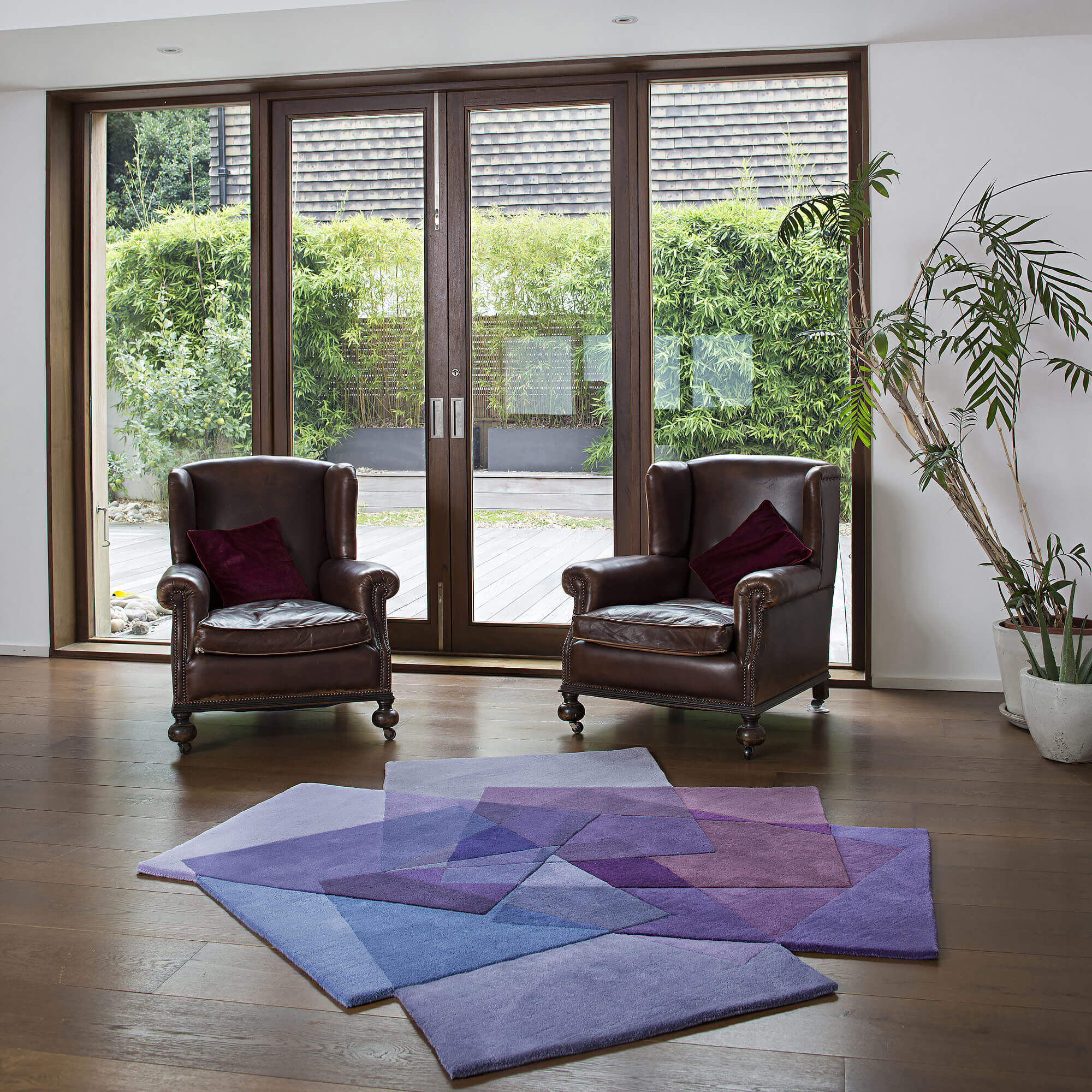 Sonya Winner After Matisse Purple rug shown in a classic living room with vintage leather armchairs and burgundy velvet seat cushions