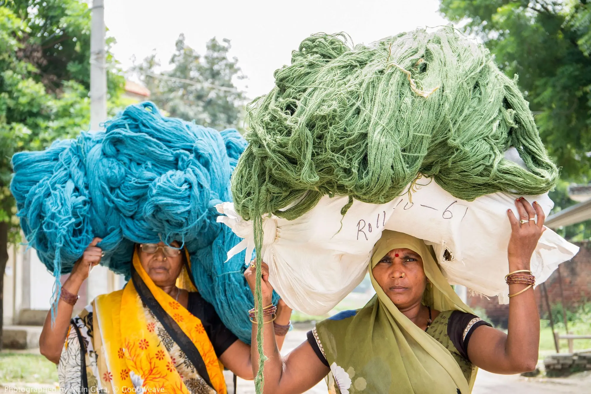 GoodWeave- women carrying yarn for rug making India (1)