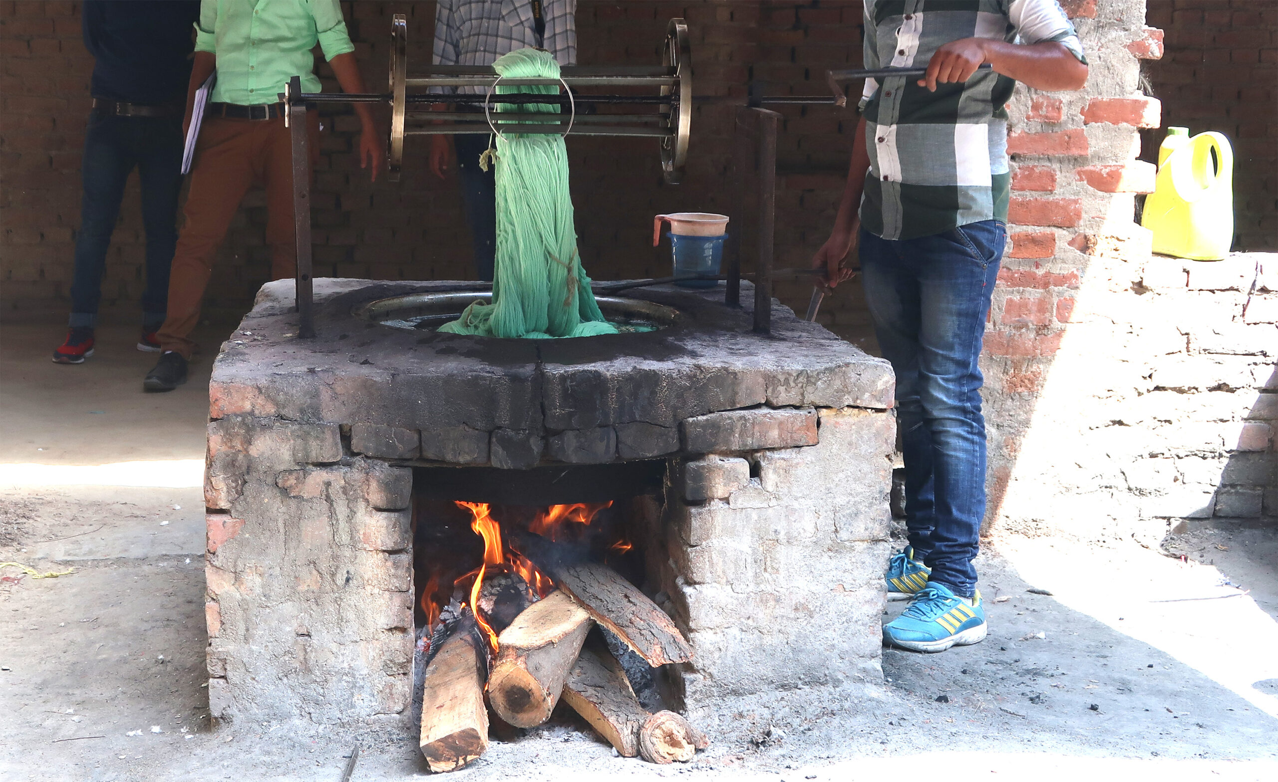 green yarn being dyed in a pot over a fire in India