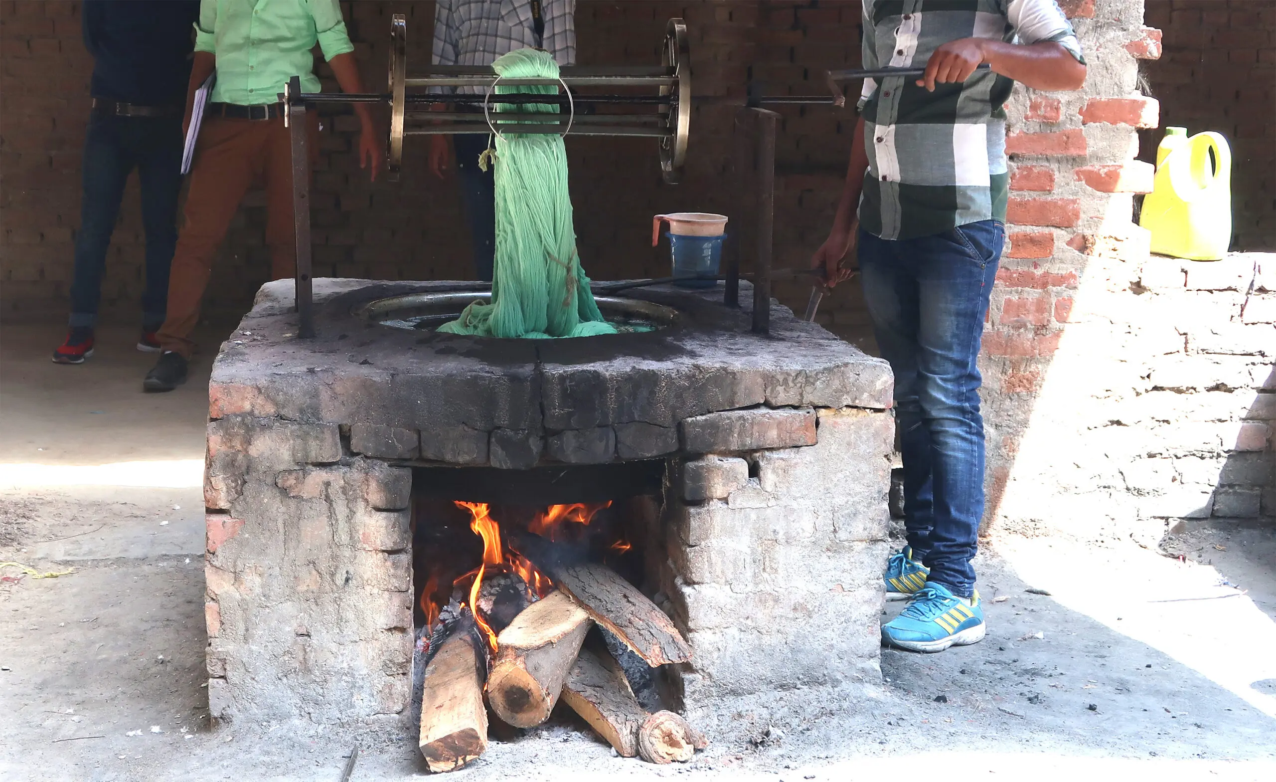 green yarn being dyed in a pot over a fire in India
